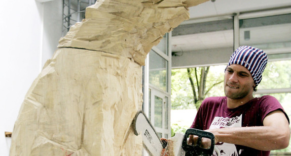 Ein Student für Bildhauerei arbeitet in einem Atelier an einer Holzskulptur. (Foto: © dpa)