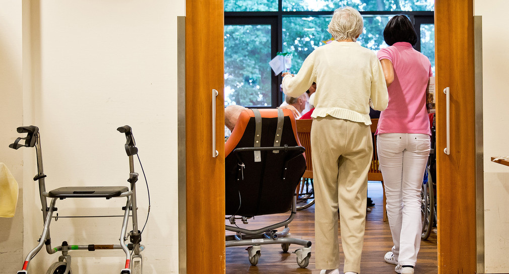 Eine auf Demenzkranke spezialisierte Pflegerin begleitet eine ältere Frau.