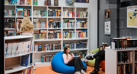 Zwie Kinder sitzen in einer Bücherei auf Sitzsäcken und lesen