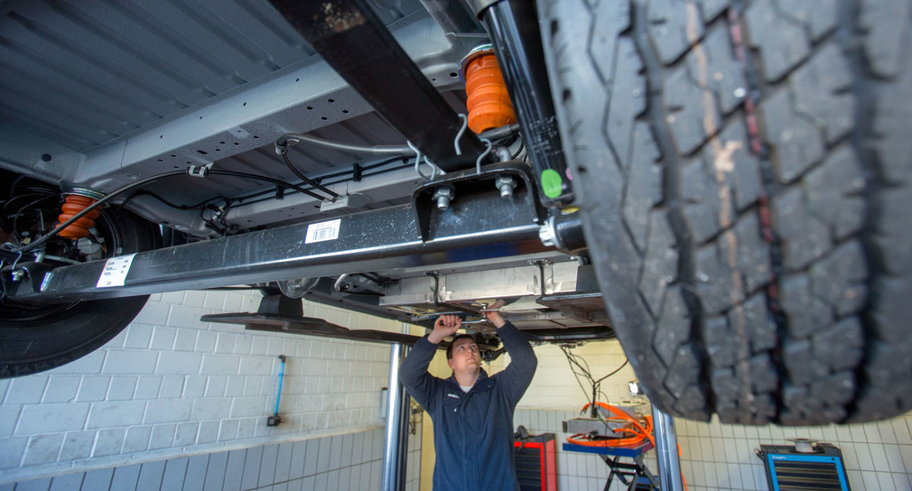 Ein Mechaniker montiert Batterieblöcke in einer Autowerkstatt. (Bild: © dpa)