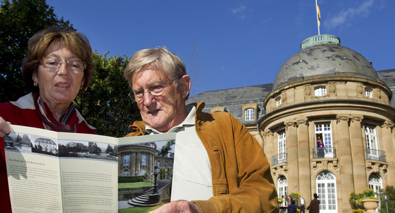 Zwei Personen stehen mit einer Broschüre im Park der Villa Reitzenstein.