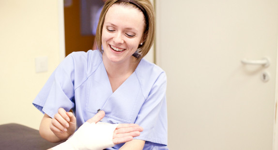 Krankenschwester verbindet die Hand eines Patienten.