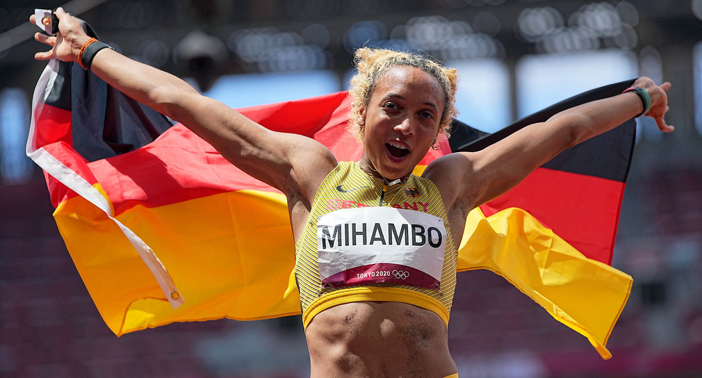 Malaika Mihambo bejubelt mit einer Deutschlandfahne ihren Olympiasieg im Weitsprung.