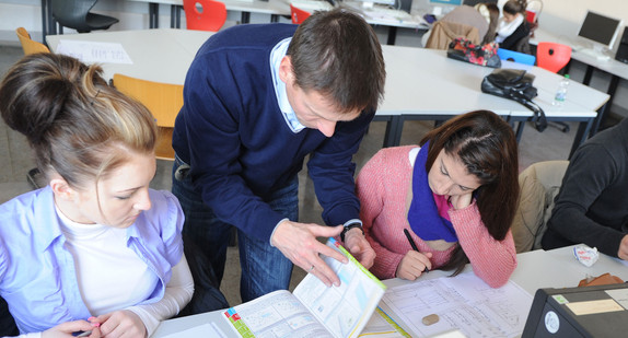 Ein Lehrer erklärt Schülerinnen etwas im Unterricht (Bild: © Ministerium für Kultus, Jugend und Sport BW).