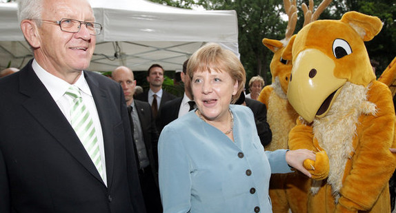 v.l.n.r.: Ministerpräsident Winfried Kretschmann, Bundeskanzlerin Angela Merkel und die Wappentiere Hirsch und Greif am Donnerstag (05.07.2012) auf der Stallwächterparty in der Berliner Landesvertretung (Foto: dpa)