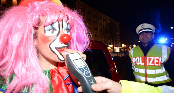 Ein als Clown verkleideter Fastnachtsnarr muss bei einer Alkoholkontrolle der Polizei in ein Messgerät pusten.