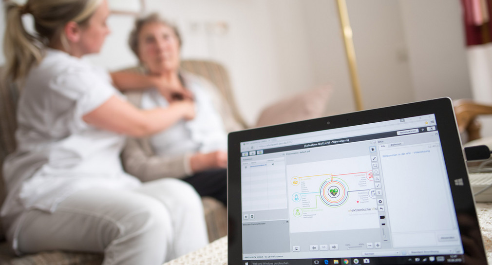 Eine Pflegerin legt der Bewohnerin einer Seniorenresidenz im Rahmen einer elektronischen Visite ein EKG-Gerät an, das die Daten an einen Tablet-Computer und von dort aus zum Arzt überträgt.