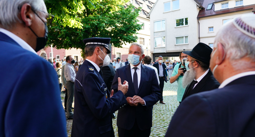Innenminister Thomas Strobl im Gespräch mit einem Polizisten beim Besuch der Synagoge in Ulm.