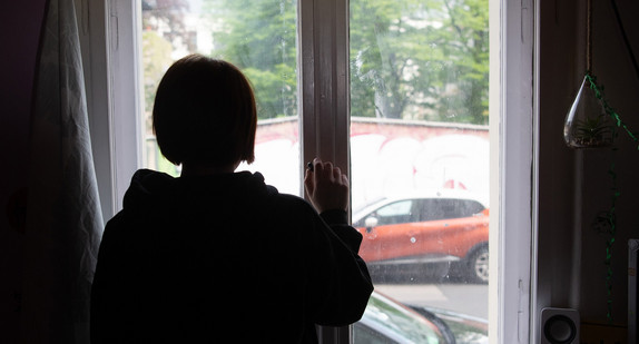 Eine Jugendliche schaut aus dem Fenster.
