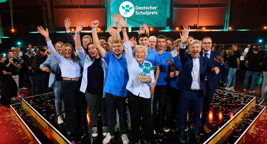 Jubelnde Vertreterinnen und Vertreter der Ferdinand-von-Steinbeis-Schule Tuttlingen mit Staatssekretär Andreas Deuschle auf der Bühne bei der Verleihung des Deutschen Schulpreises