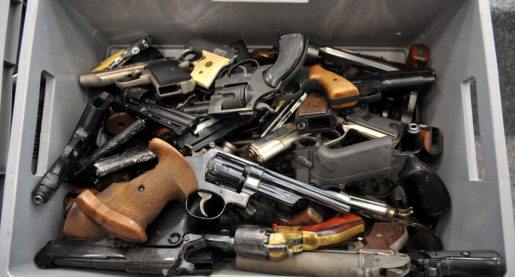 Abgegebene Schusswaffen liegen im Polizeipräsidium in einer Kiste (Bild: © dpa).