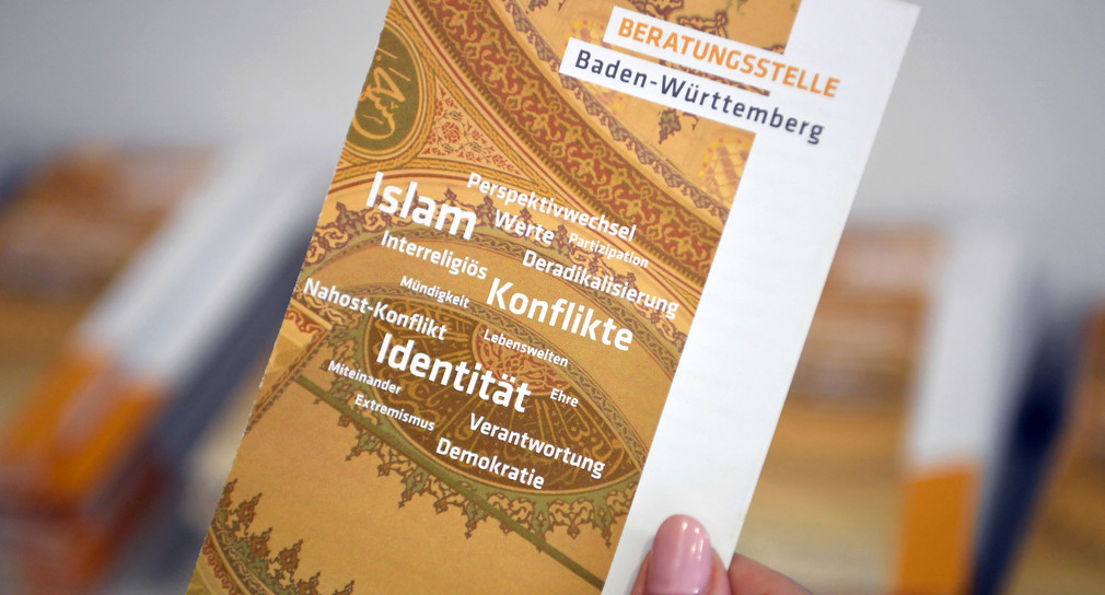 Eine Frau hält während der Einweihung der Räumlichkeiten der Beratungsstelle Baden-Württemberg für radikalisierte Menschen und deren Angehörige ein Faltblatt in der Hand. (Foto: © dpa)