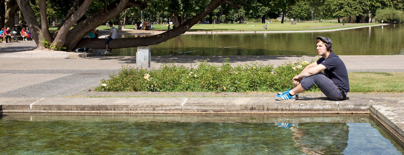 Junger Mann Hoert Musik Im Park 700x360 A young man sitting in a park listening to some tunes.