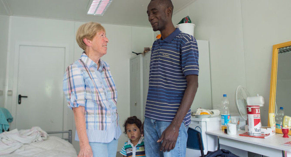 Eine ehrenamtliche Helferin spricht in Schwetzingen in der Flüchtlingsunterkunft mit einem Flüchtling aus Gambia (Foto: dpa)