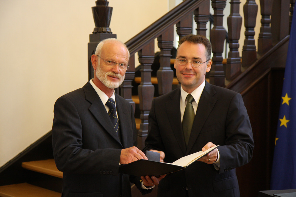Minister Peter Friedrich überreicht Ulrich Scheller aus Engen die Staufermedaille.