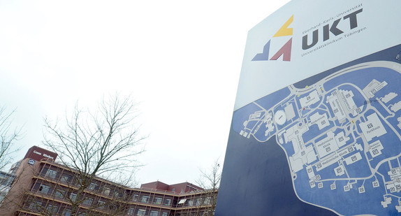 Ein Logo mit einem Hinweisschild des Universitätsklinikums Tübingen steht vor einem Klinikgebäude in Tübingen. (Foto: dpa)