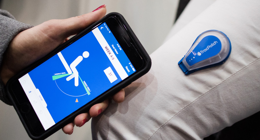 Ein Model trägt auf der Messe Medica ein intelligentes Pflaster, das den Wundheilungsprozess mittels Temperaturmessung überwacht und an eine App auf dem Smartphone sendet.