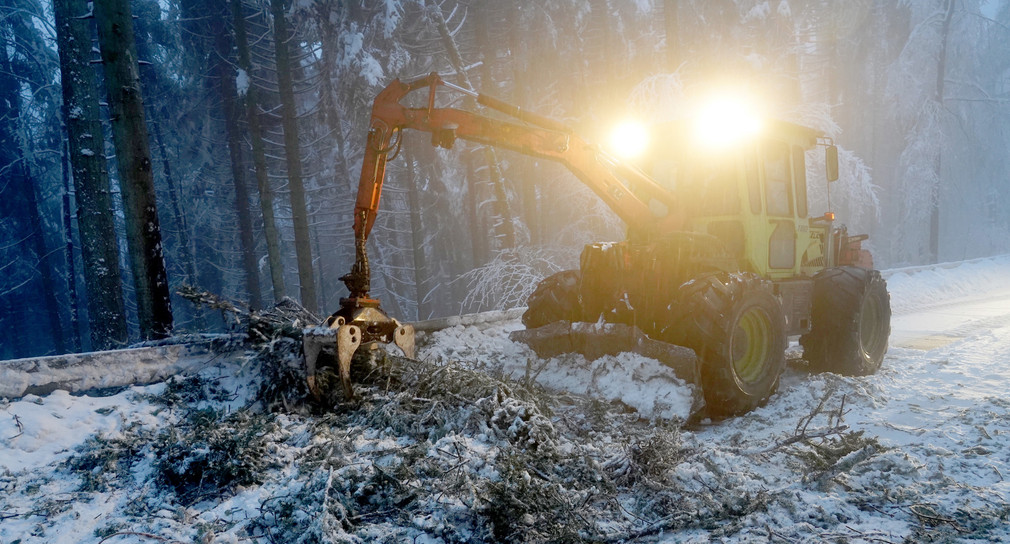Ein Forstfahrzeug räumt nach einem Schneebruch eine Landstraße frei (Bild: © dpa)