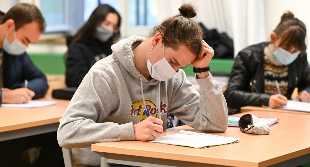 Schülerinnen und Schüler des Spohn-Gymnasiums in Ravensburg sitzen bei geöffnetem Fenster mit Mund- und Nasenschutz im Unterricht.
