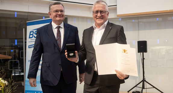  Ministerialdirektor Elmar Steinbacher und Alexander Schmid mit Urkunde und Medaille.