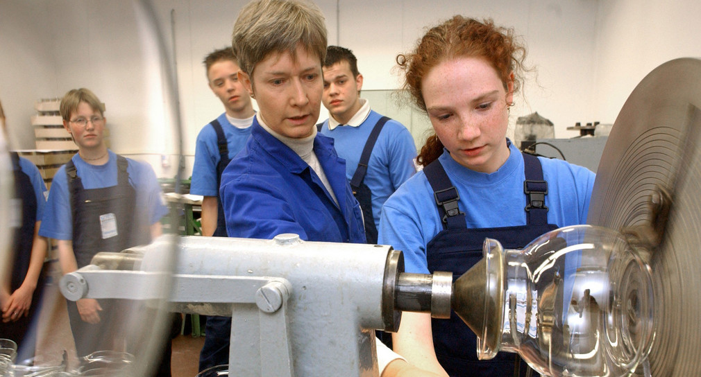 Eine Schülerin bearbeitet unter Anleitung einer Lehrausbilderin bei einer „Schnupperlehre“ ihr erstes gläsernes Werkstück. (Foto: © dpa)