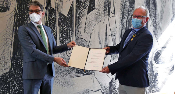 Staatssekretär Dr. Andre Baumann (links) und Prof. Dr. Andreas Krautter (rechts) mit der Urkunde zur Verleihung des Verdienstordens des Landes Baden-Württemberg.