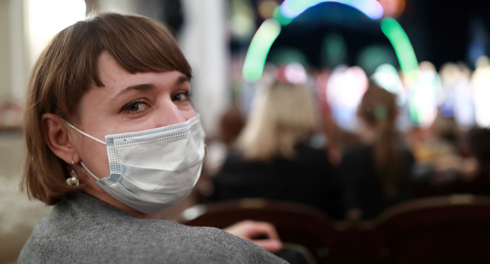 Eine Frau sitzt mit einer OP-Maske in einer Theatervorstellung.