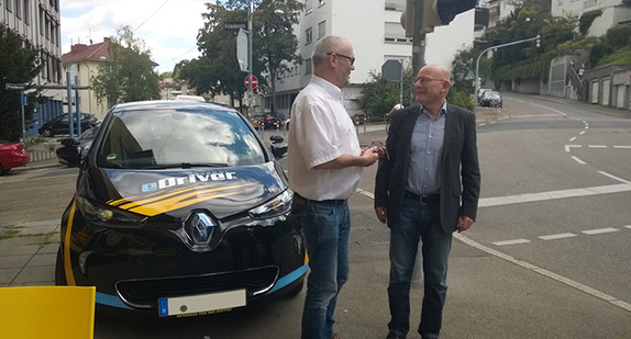 Minister Winfried Hermann (r.) steht neben dem ersten landesgeförderten Elektro-Fahrschulfahrzeug 