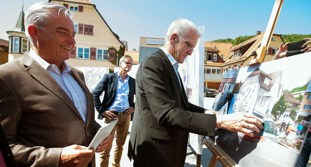Ministerpräsident Kretschmann (r.) und Innenminister Thomas Strobl (l.) setzen am 26.05.2017 in Braunsbach ein Bild zusammen, welches den Zustand von Braunsbach heute und nach dem Unwetter vor einem Jahr zeigt. (Foto: © dpa)