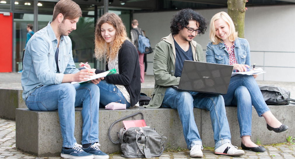 Studierende sitzen vor der Hochschule der Medien (Foto: © Hochschule der Medien Stuttgart/Sven Cichowicz)
