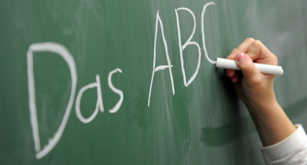 Eine Schülerin schreibt das ABC an die Tafel. (Foto: dpa)