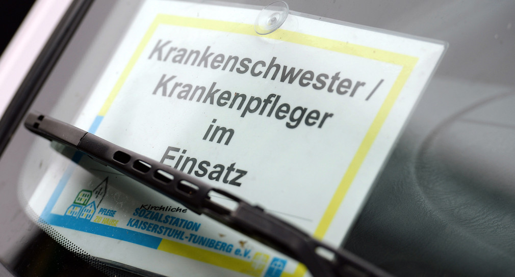 Ein Hinweisschild "Krankenschwester/Krankenpfleger im Einsatz" ist hinter einer Windschutzscheibe eines parkenden Autos in Freiburg angebracht. (Bild: picture alliance/Patrick Seeger/dpa)