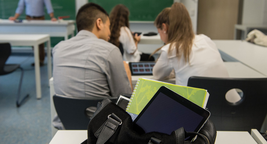 Ein Tabletcomputer ragt in einem Klassenzimmer aus der Tasche einer Schülerin. (Foto: © dpa)