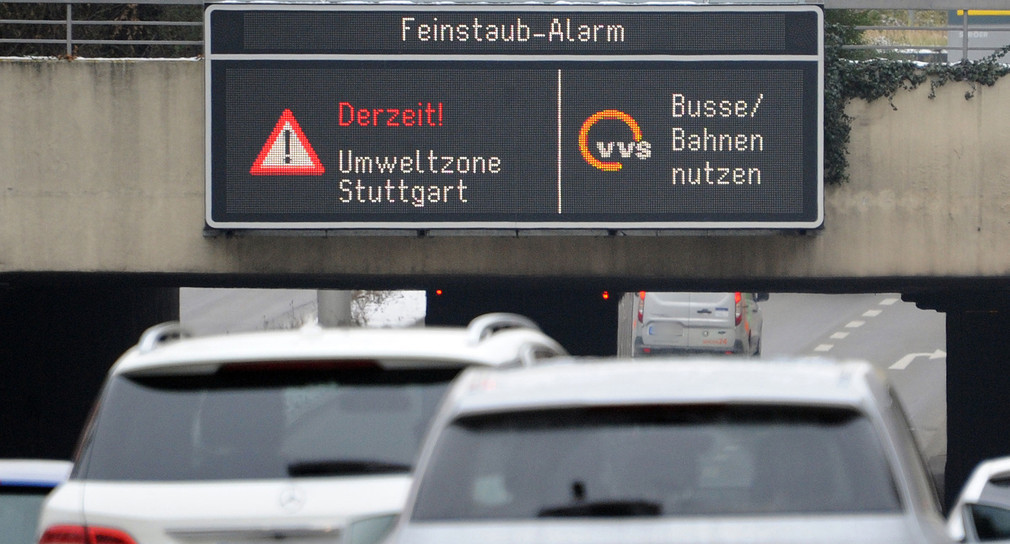 Autos fahren in Stuttgart durch die Innenstadt unter einer Anzeige «Feinstaub Alarm» für die Umweltzone Stuttgart entlang (Quelle: dpa).