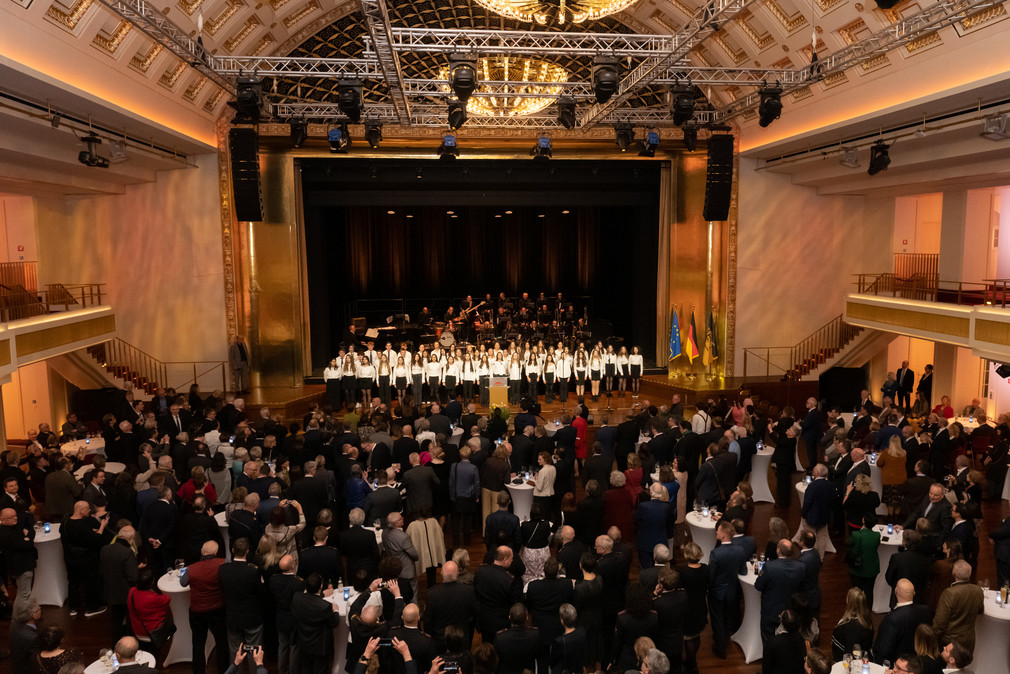 Blick in das Kurhaus in Baden-Baden: Die Gäste stehen im Saal, im Hintergrund auf der Bühne sorgen die Landes-Lehrer-Bigband Baden-Württemberg sowie der Chor des Pädagogium Baden-Baden für die musikalische Umrahmung des Empfangs.