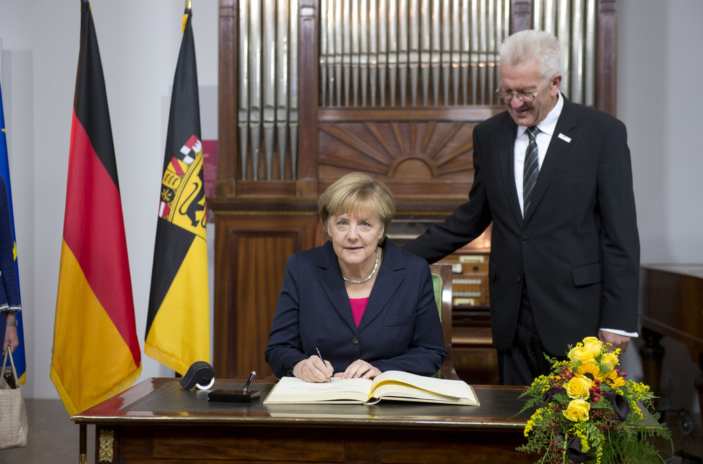 Bundeskanzlerin Angela Merkel (l.) beim Eintrag in das Gästebuch der Landesregierung und Bundesratspräsident Winfried Kretschmann (r.)
