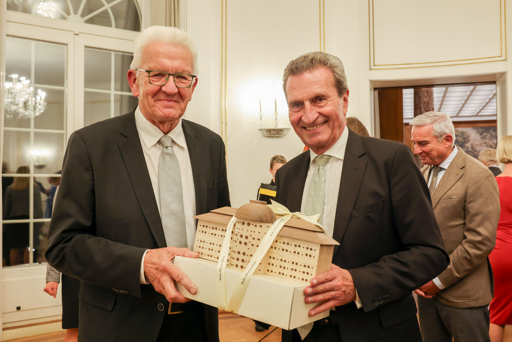 Ministerpräsident Winfried Kretschmann (links) überreicht dem ehemaligen Ministerpräsidenten Günther Oettinger (rechts) bei einem Empfang anlässlich dessen 70. Geburtstages ein Bienenhotel in Form der Villa Reitzenstein.
