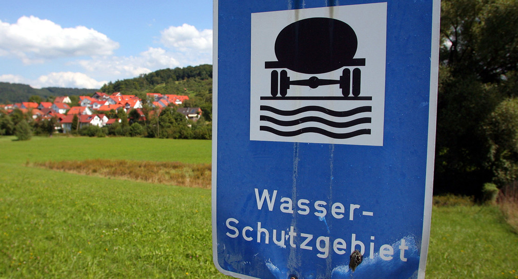 Ein Schild, das auf ein Wasserschutzgebiet hinweist, steht an einer Wiese. (Foto: dpa)