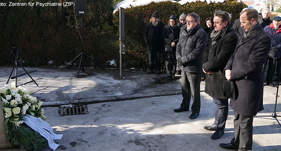 Ravensburgs Oberbürgermeister Dr. Daniel Rapp, Minister Manne Lucha und der Geschäftsführer der ZfP Südwürttemberg und des Zentrums für Psychiatrie Reichenau Dr. Dieter Grupp schauen auf niedergelegten Kranz am Mahnmal der Grauen Busse.