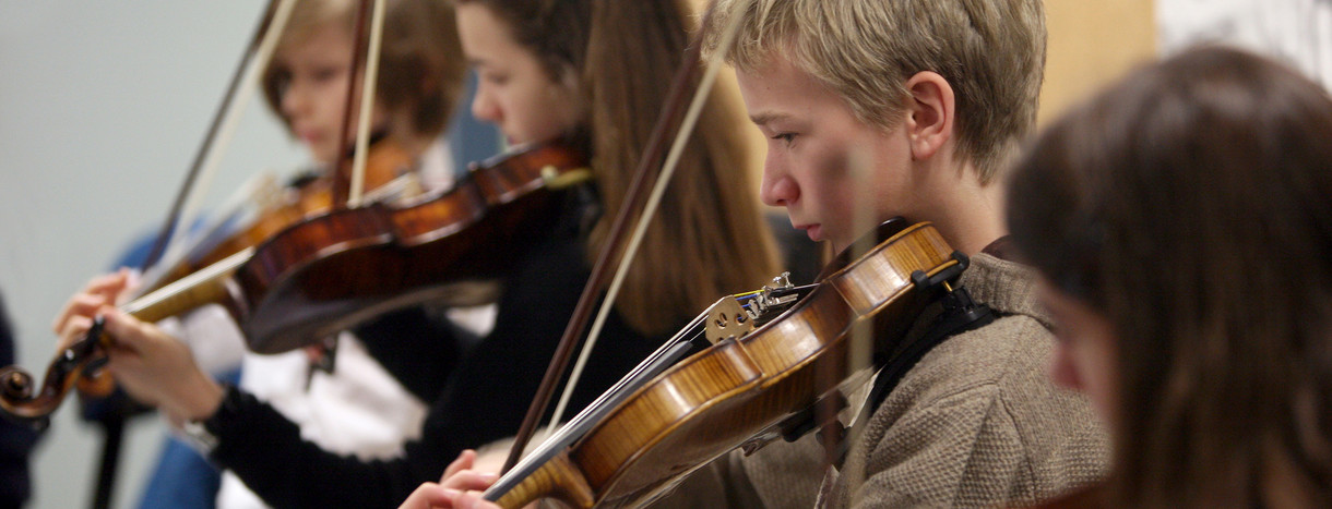 Schüler eines Musikgymnasiums spielen Geige.