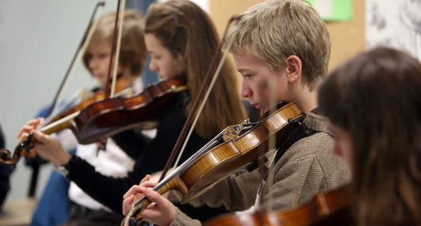 Schüler eines Musikgymnasiums spielen Geige.