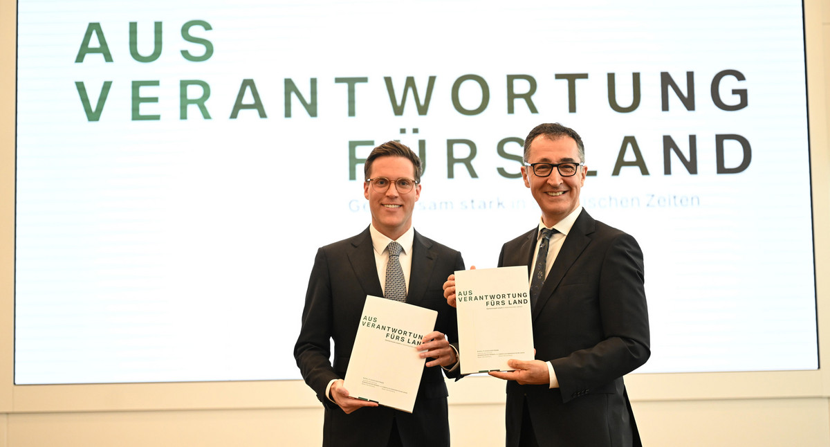 Cem Özdemir (rechts) und und Manuel Hagel (links) präsentieren den Koalitionsvertrag von BÜNDNIS 90/DIE GRÜNEN und CDU. Auf den von den beiden gezeigten Publikationen und einem Hintersteller steht der Schriftzug „AUS VERANTWORTUNG FÜRS LAND - Gemeinsam stark in stürmischen Zeiten“.