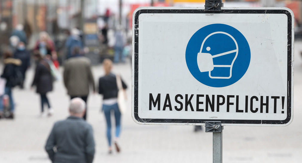 Maskenpflicht-Schild in einer Fußgängerzone.