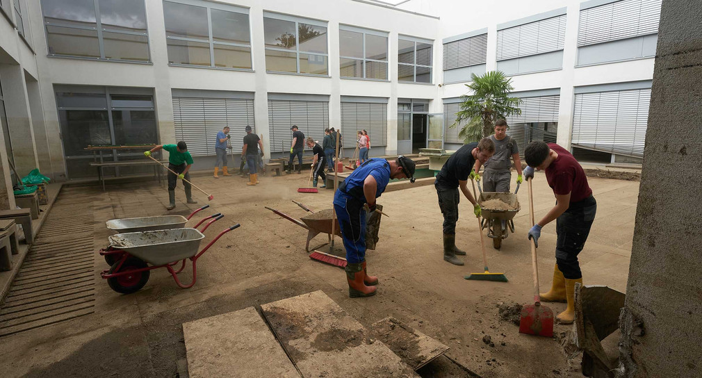 Freiwillige Helfer reinigen einen Innenhof der Boeselager-Realschule, die durch die Flutkatastrophe stark beschädigt wurde.