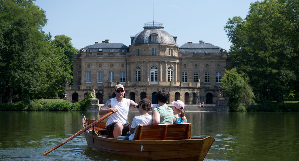 Eine Familie sitzt vor dem Seeschloss Monrepos in Ludwigsburg einem Ruderboot. 