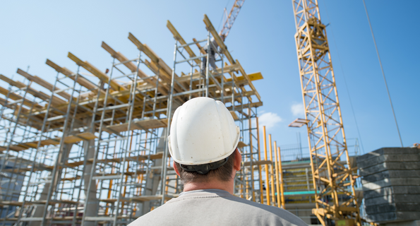 Ein Bauarbeiter schaut auf ein Gebäude, das als Testobjekt aus Recyclingbeton gebaut wird. 