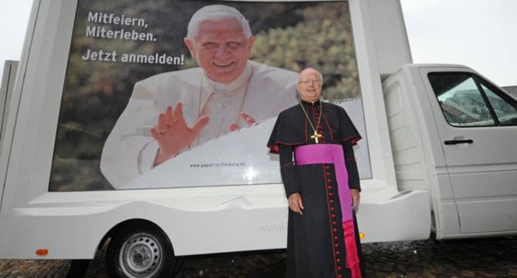 Erzbischof Robert Zollitsch in Freiburg vor einem überdimensionalen Bild von Papstes Benedikt XVI auf einem "Litomobil". (Foto: dpa)