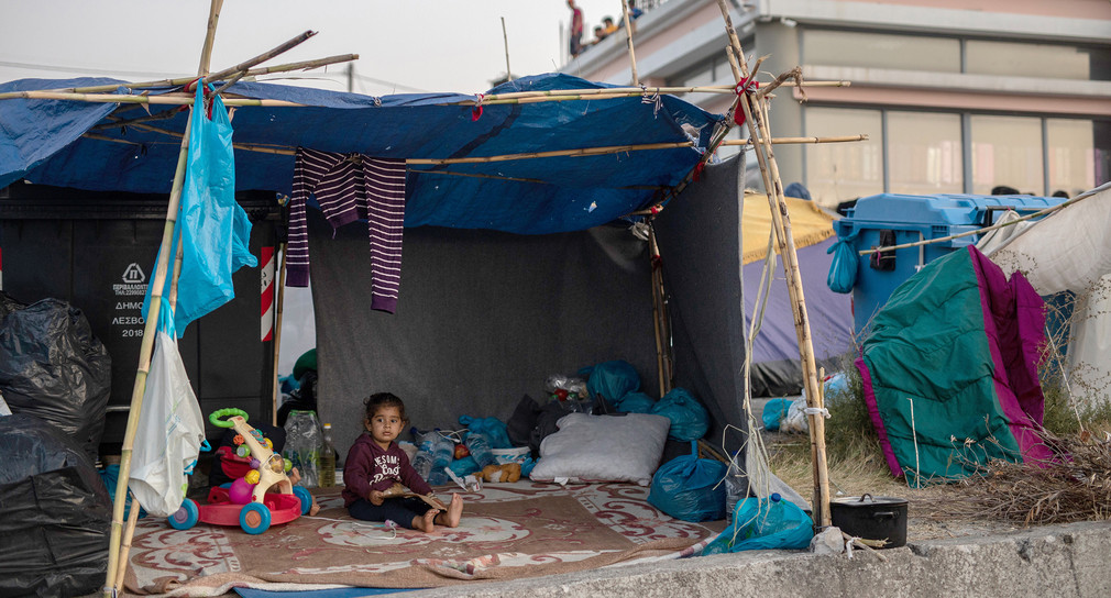 Ein Kind sitzt in einem provisorischen Zelt entlang einer Straße welche von Moria nach Mytilene führt. (Bild: picture alliance/Petros Giannakouris/AP/dpa)
