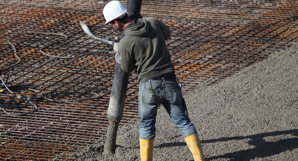 Ein Bauarbeiter füllt eine Fläche auf einer Baustelle mit Beton.