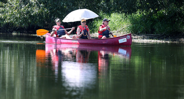 Kanufahrer mit einem Sonnschirm in der Hand sind auf der Donau bei Riedlingen unterwegs (Bild: © dpa).